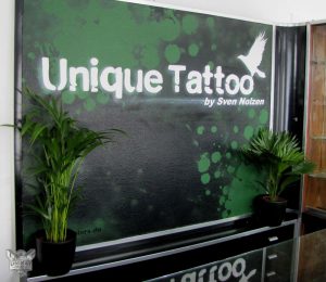 Unique tattoo Logo auf Wand im Eingang